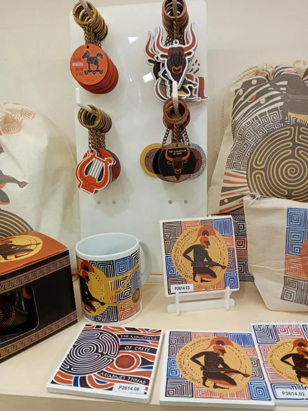 Συλλογή ελληνικών σουβενίρ με θέμα Θησέας και Μινώταυρος – μπρελόκ, κούπα, σουβέρ και υφασμάτινες τσάντες σε display