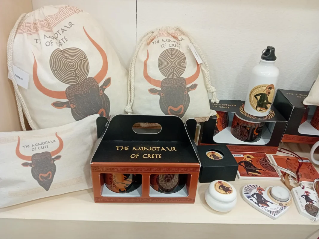 Συλλογή ελληνικών σουβενίρ με Μινώταυρο Κρήτης – υφασμάτινες τσάντες, σετ κούπας, παγούρι και κεραμικά δώρα σε βιτρίνα